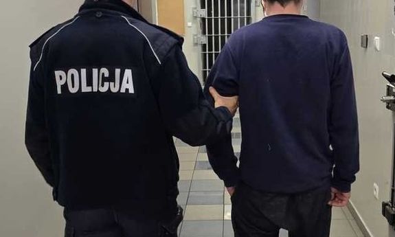 policjant idzie z zatrzymanym.