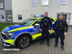 Dwaj policjanci przy radiowozie.