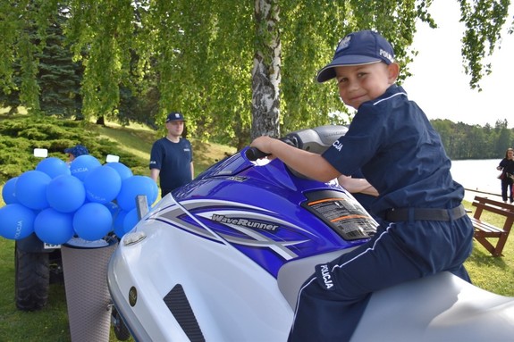 Dziecko w policyjnym mundurze na skuterze.