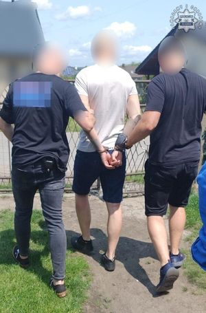 Dwaj nieumundurowani policjanci prowadzą zatrzymanego.