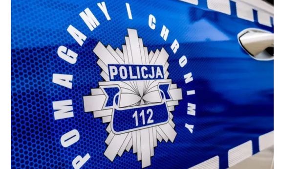 Policyjna odznaka na drzwiach radiowozu a wokół niej hasło: pomagamy i chronimy.