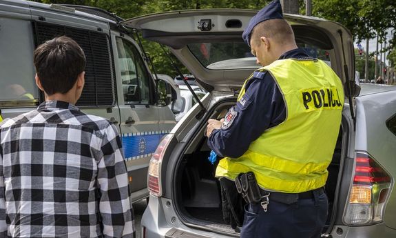 policjant sprawdza bagażnik pojazdu.