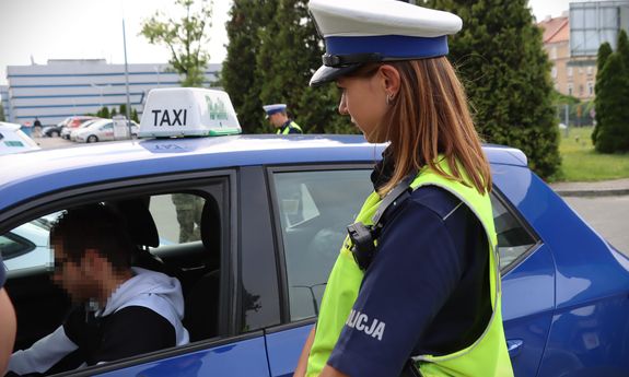 Policjantka ruchu drogowego przy aucie przewożącym osoby na aplikację.