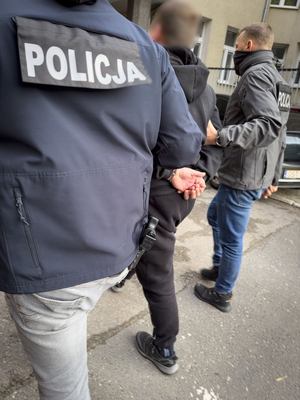 Dwaj nieumundurowani policjanci prowadzą zatrzymanego.