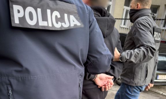 Dwaj nieumundurowani policjanci prowadzą zatrzymanego.