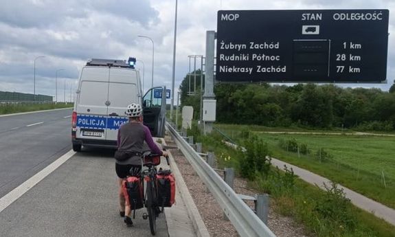 kobieta jedzie rowerem po autostradzie.