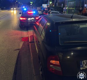 Policjanci przy radiowozie i zatrzymany nietrzeźwy kierujący.