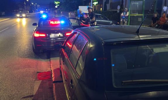 Policjanci przy radiowozie i zatrzymany nietrzeźwy kierujący.