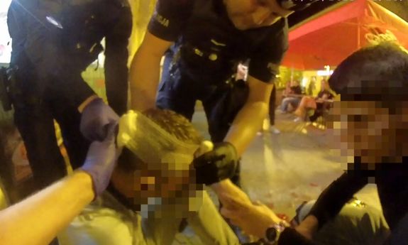 Stop klatka z filmu, na którym policjanci udzielają pomocy krwawiącemu mężczyźnie.
