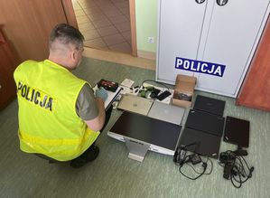 Policjant i zabezpieczony sprzęt elektroniczny.