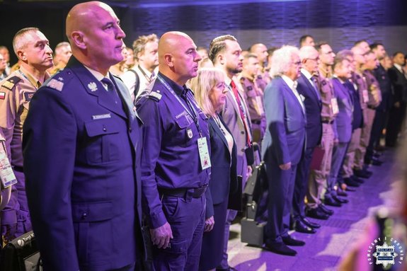 Policjanci w mundurach i zebrani goście na sali podczas targów.