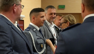 Kobieta przypina policjantowi odznaczenie.