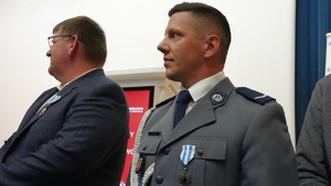Wyróżniony policjant, obok mężczyzna w garniturze.