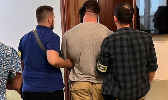 dwóch policjantów idzie z zatrzymanym.