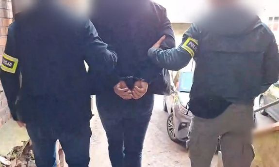 dwóch policjantów prowadzi zatrzymanego.