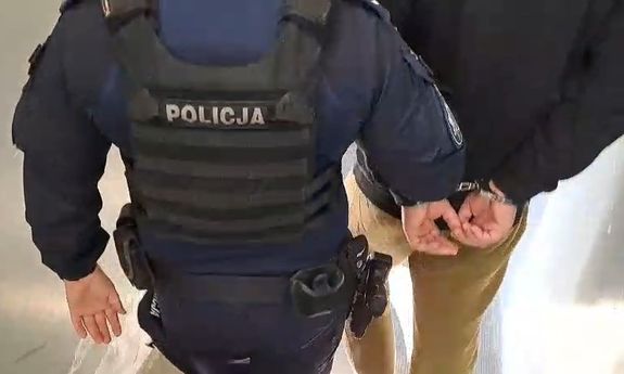 policjant idzie z zatrzymanym.