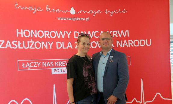 Odznaczony policjant w garniturze  z kobieta pozują do zdjęcia.