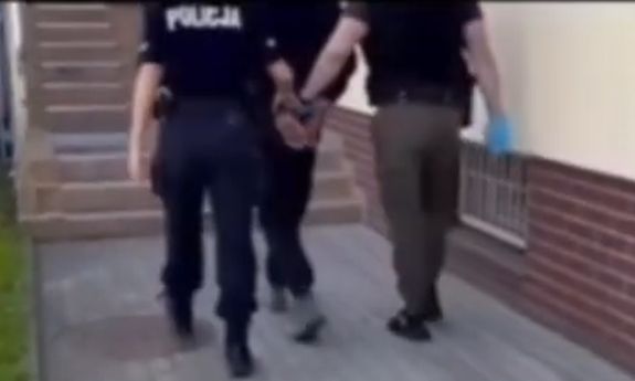 policjanci idą z zatrzymanym.