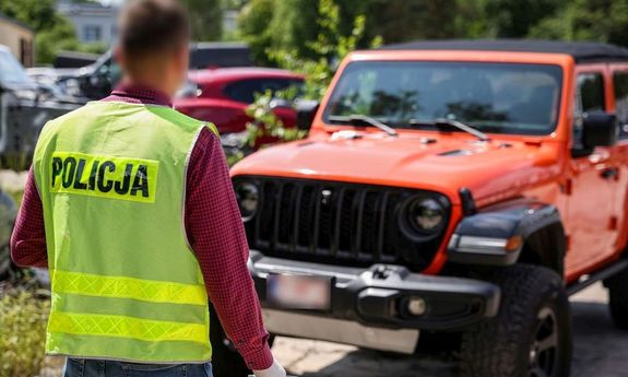 policjant patrzy na jeden z rozebranych samochodów.