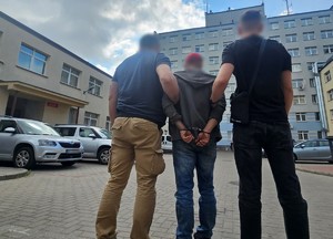 dwóch policjantów stoi z zatrzymanym.