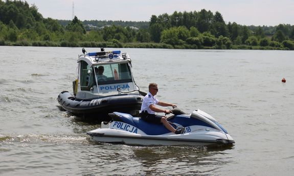 Na zdjęciu woda, a na niej skuter policyjny, którym kieruje policjant oraz łódź policyjna, za sterami której znajduje się policjant.