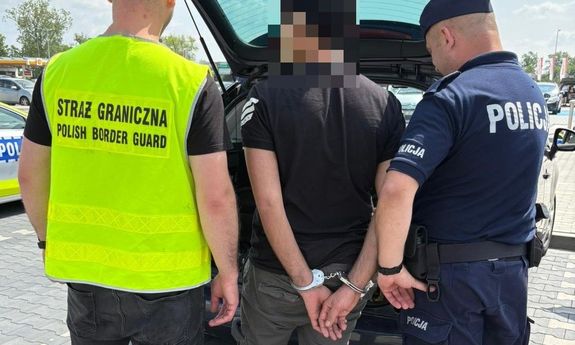Funkcjonariusze Policji i Straży Granicznej z zatrzymanymi przy aucie.