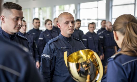 Policjantka wręcza funkcjonariuszom puchar.