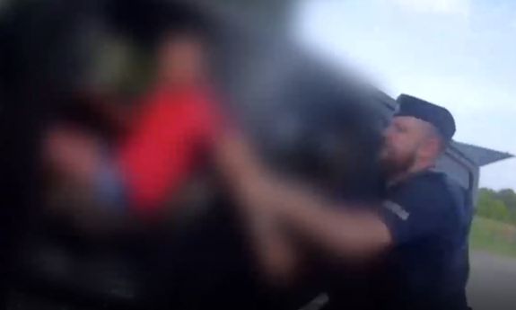 policjant wyciąga z samochodu pijanego mężczyznę.