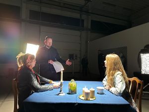 Na zdjęciu dwie kobiety siedzące przy stole, a obok nich stoi umundurowany policjant. W tle stoją kolejne dwie osoby.