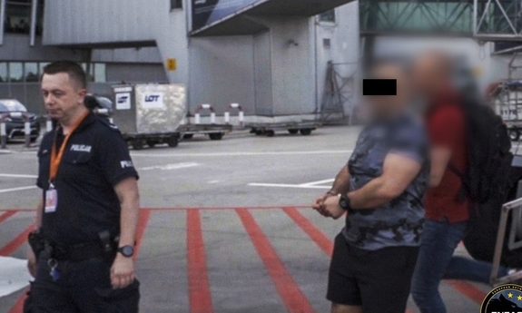 Zatrzymany mężczyzna prowadzony przez policjantów.