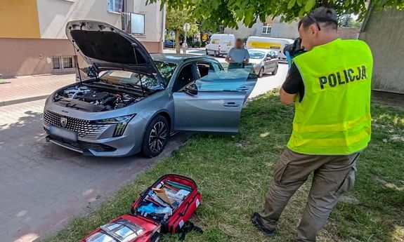Policjant prowadzi oględziny samochodu.