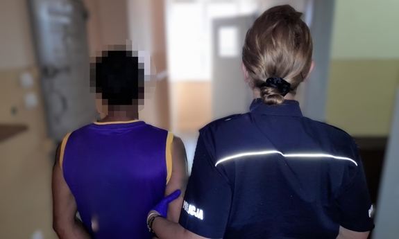 Policjantka z zatrzymanym mężczyzna zakutym w kajdanki.