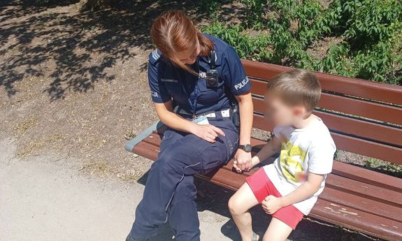 Policjantka siedzi z dzieckiem na ławce.
