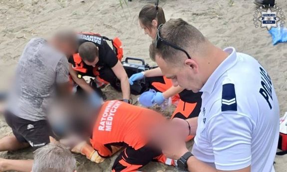 Policjant i strażacy udzielają pomocy.