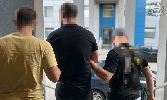 Dwaj policjanci prowadzą zatrzymanego.