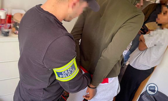 Policjant CBZC prowadzi zatrzymanego.