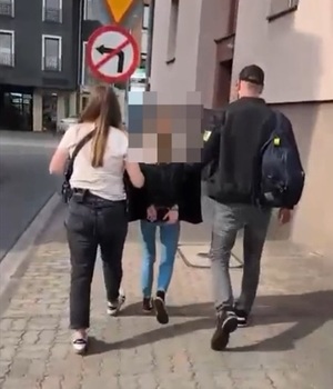 dwóch policjantów idzie z zatrzymaną.