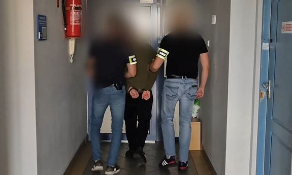 Dwaj nieumundurowani policjanci prowadzą zatrzymanego - widok z tyłu.