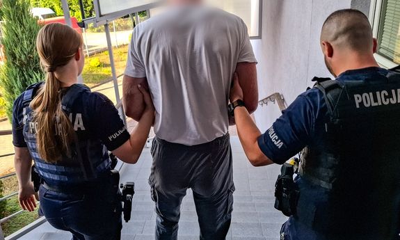 Dwoje umundurowanych policjantów prowadzi zatrzymanego.