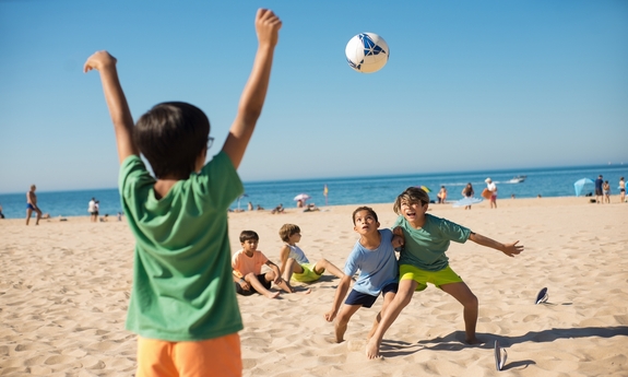 Grupa dzieci gra w piłkę na plaży.
