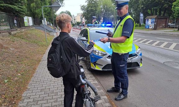policjant stoi obok rowerzysty i uśmiecha się do niego.