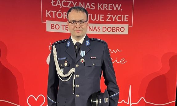 Policjant w mundurze pozuje do zdjęcia.