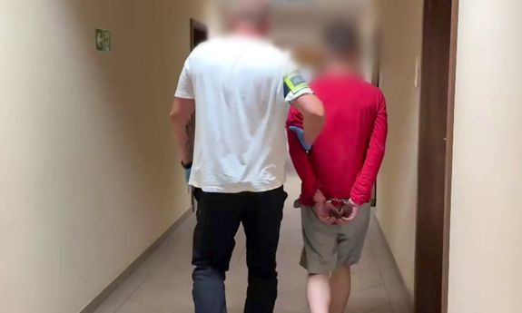 Policjant ubrany po cywilnemu prowadzi zatrzymanego.