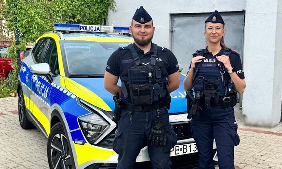Dwoje policjantów z patrolu, za nimi radiowóz.