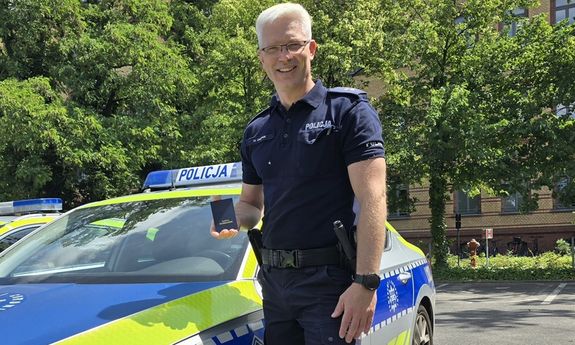 Policjant stoi przy radiowozie.