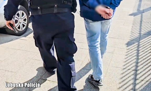 Policjant prowadzi zatrzymanego.