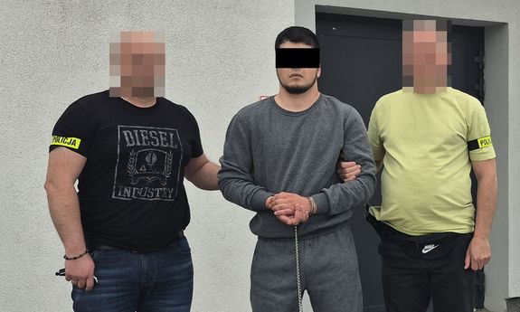 Zatrzymany mężczyzna prowadzony przez dwóch nieumundurowanych policjantów. Widok - z przodu.