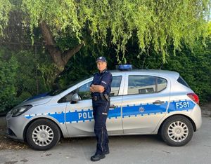 Policjantka stoi przy radiowozie.