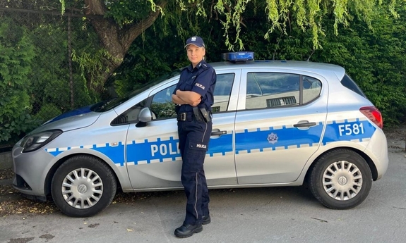 Policjantka stoi przy radiowozie.
