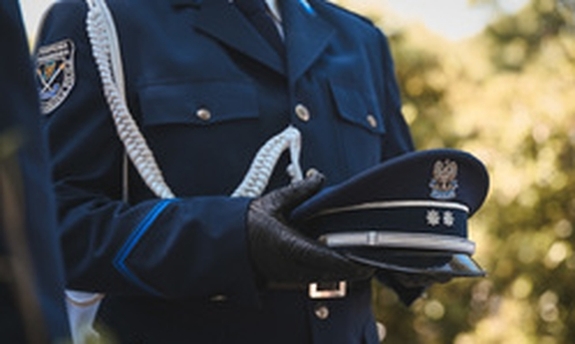 Policjant trzyma w rękach czapkę.